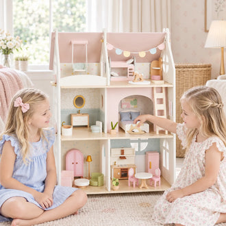 Two girls playing with the Cloud Cottage wooden dollhouse in pink and sage